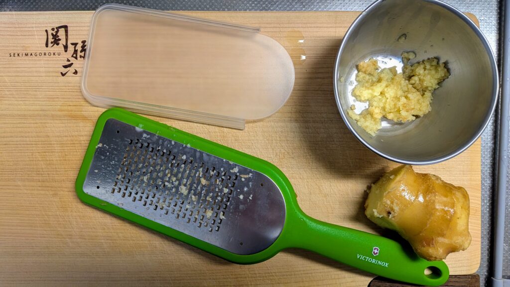 まな板の上に乗っている、VICTRINOXグレーター(細目)で皮ごとすり下ろされた細目のおろししょうが