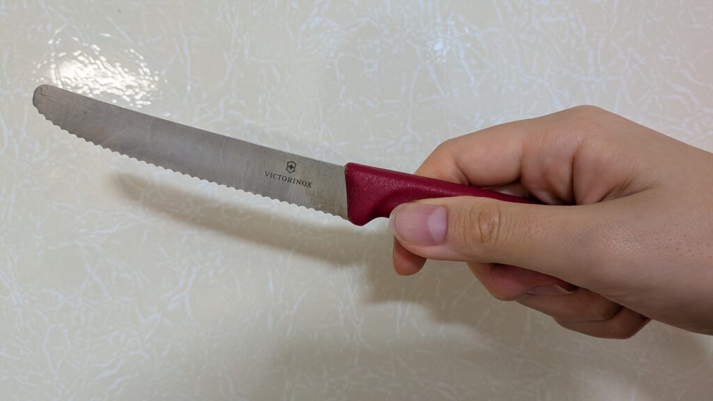 VICTORINOX(ビクトリノックス)スイスクラシック トマト&テーブルナイフ(赤)を持つ写真。