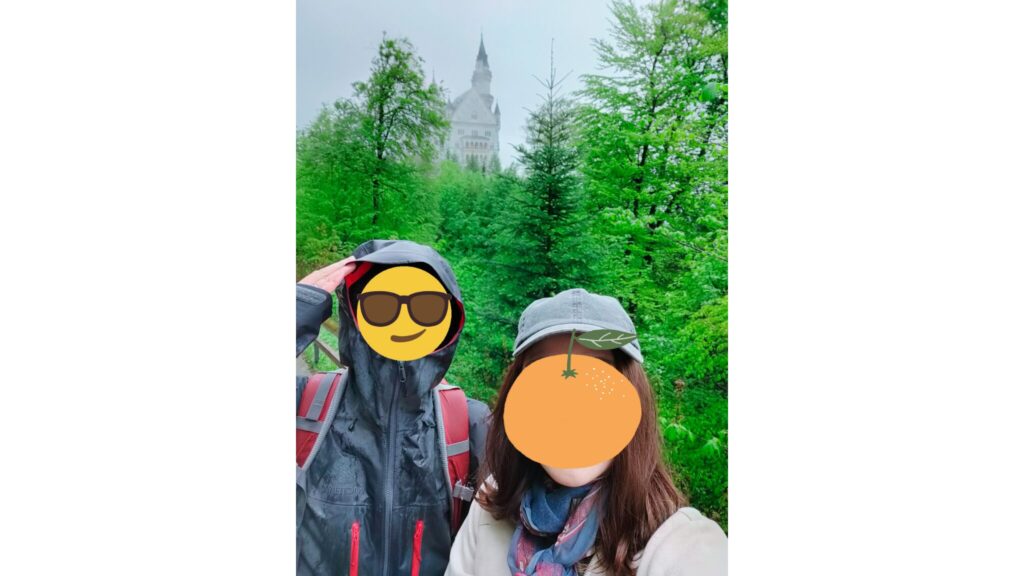 ノイシュバンシュタイン城ふもとで撮影した城と森に囲まれた記念写真