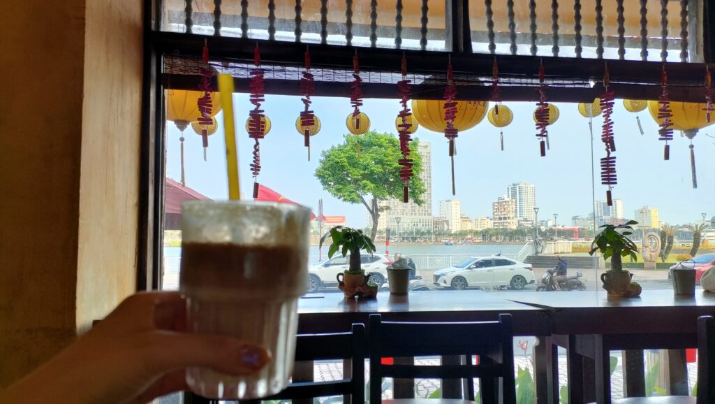ハン川を眺められるÚt Tịch Caféの窓際席で、ココナッツコーヒーを楽しむ
