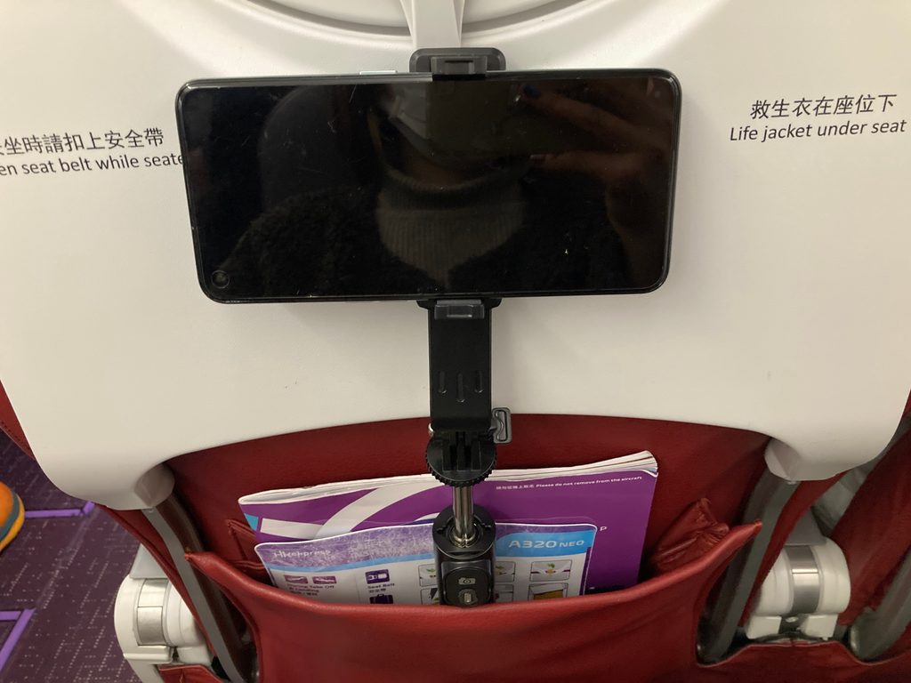 機内の座席に自撮り棒を挿してスマホスタンドとして使う様子